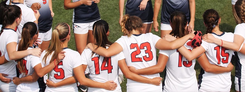Photo of women's athletic team in a huddle on the field