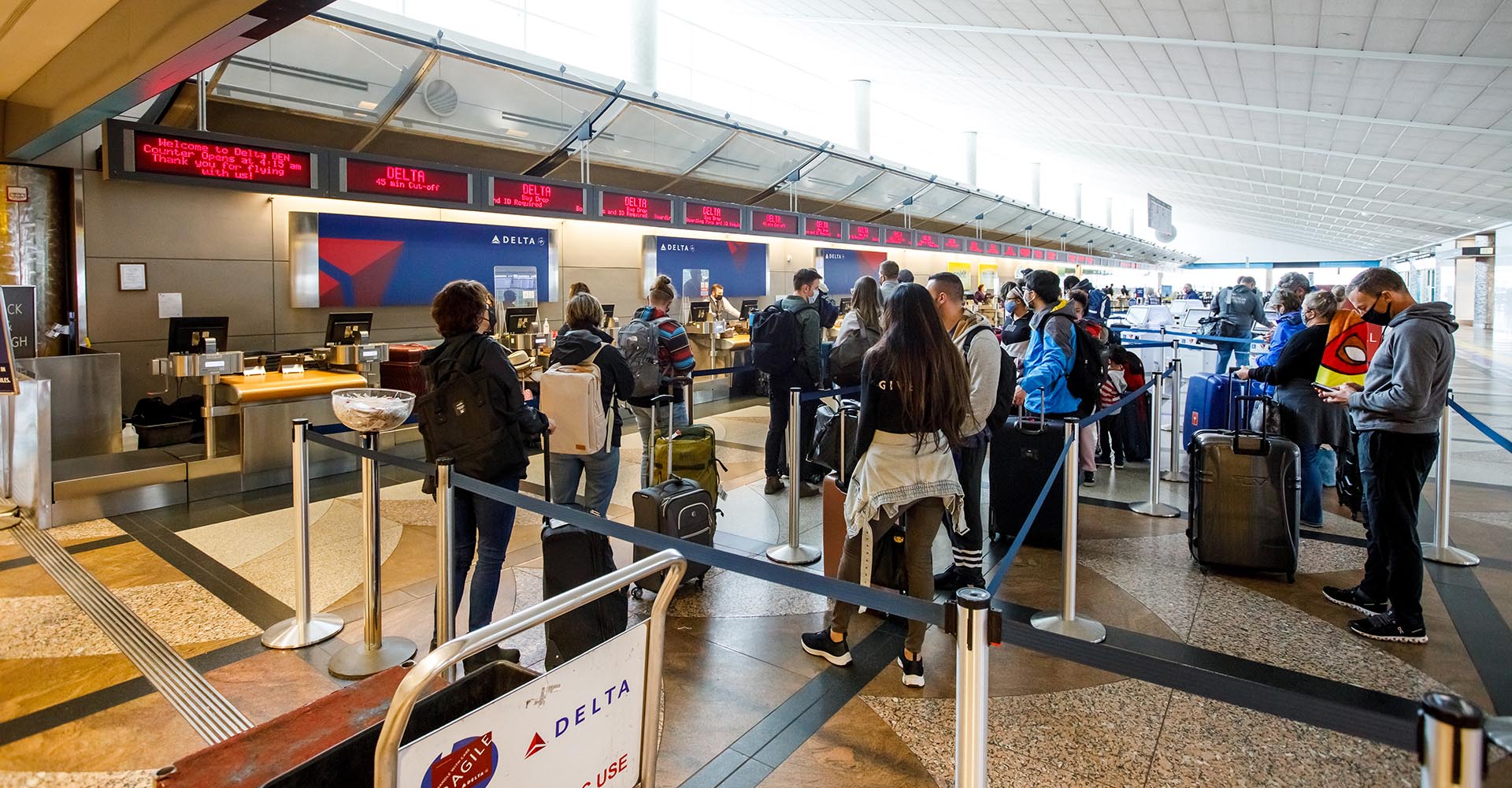 Travelers stand in line at the Denver International Airport terminal