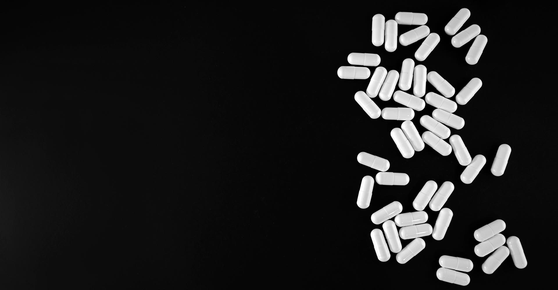 White pills cascading down a black background
