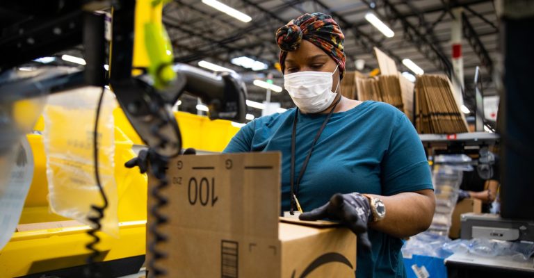 Amazon employee handles a package at a warehouse facility