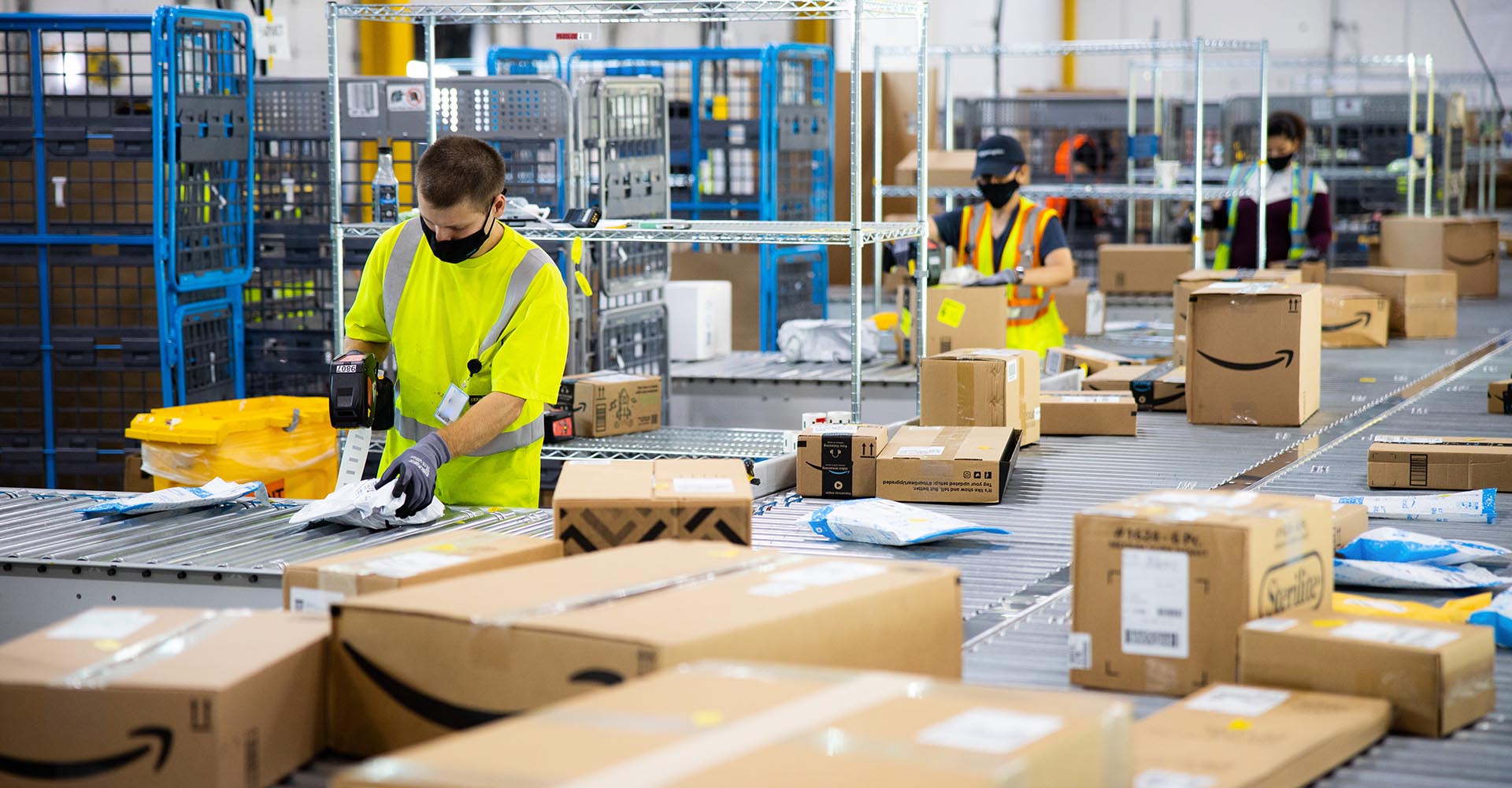 Amazon workers handle packages at a distribution warehouse