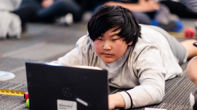 Un estudiante trabaja en una computadora en un campamento de verano