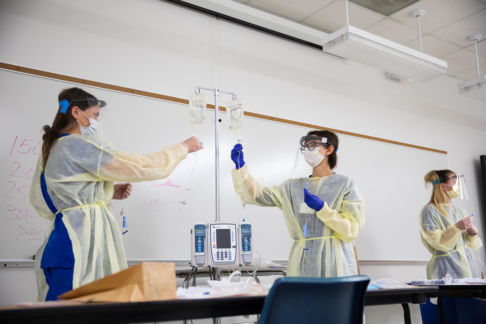 MSU Denver nursing students Victoria Whitley, left, Alexia Girin, and Erin Apple practice foundational hands on skills including priming tubing for IVs with instructor Jenny Bielefeld on Wednesday, April 22, 2020 in the Boulder Creek building on campus.
