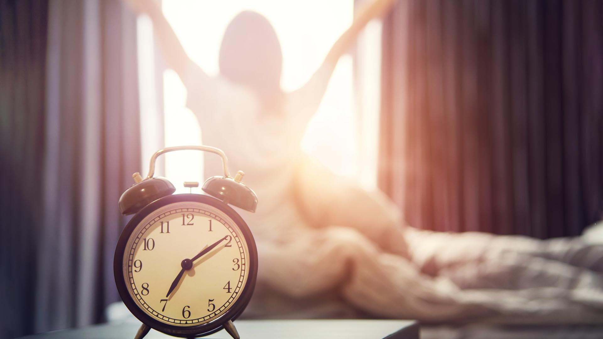 Alarm clock and morning light, girl stretching