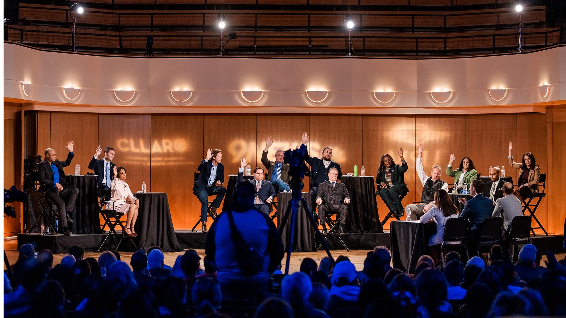 Mayoral candidates raise their hands to answer questions during the debate