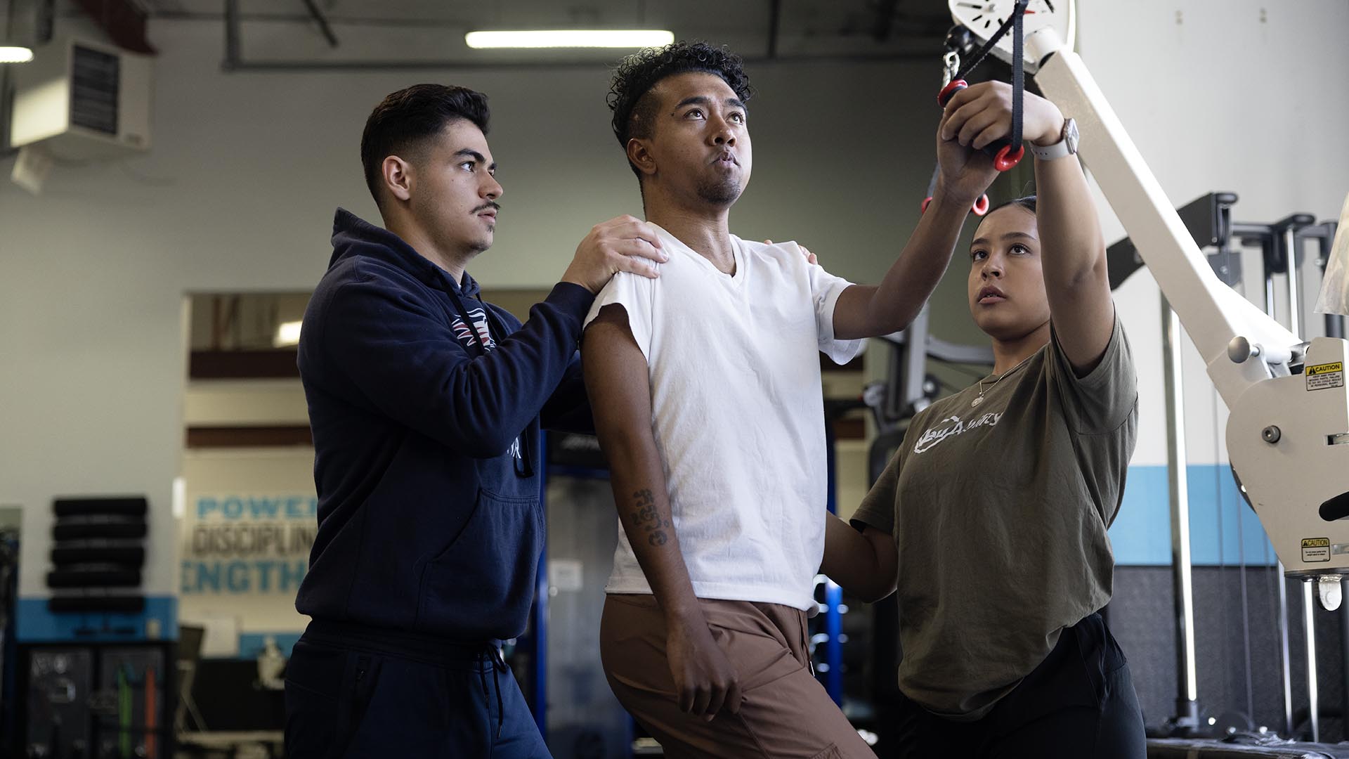 MSU Denver Exercise Science students Humberto Pallares, left, and Aranely Dominguez assist NeuAbility client Tyler Wesley with his exercises