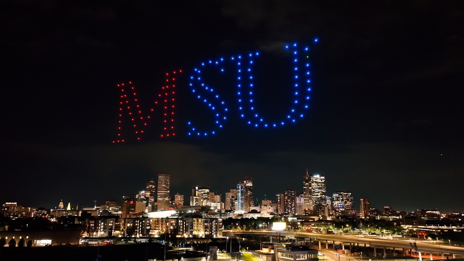 An arial image of Denver downtown with MSU letters in the sky made with drones.
