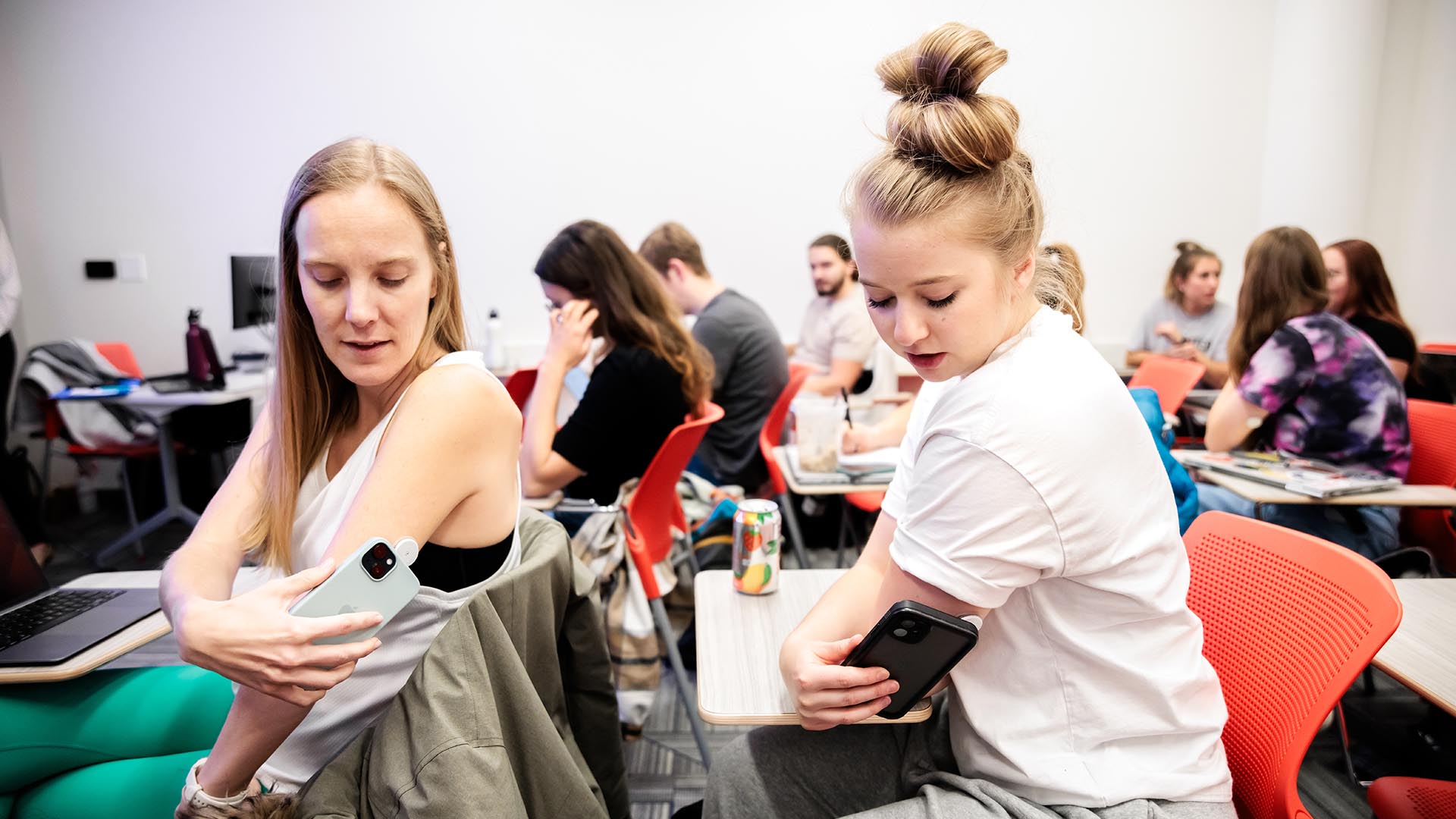 MSU Denver students Sarah McDonald, left, and Jackie Warner use their phones and the FreeStyle Libre system application to scan the sensor which is a continuous glucose monitor