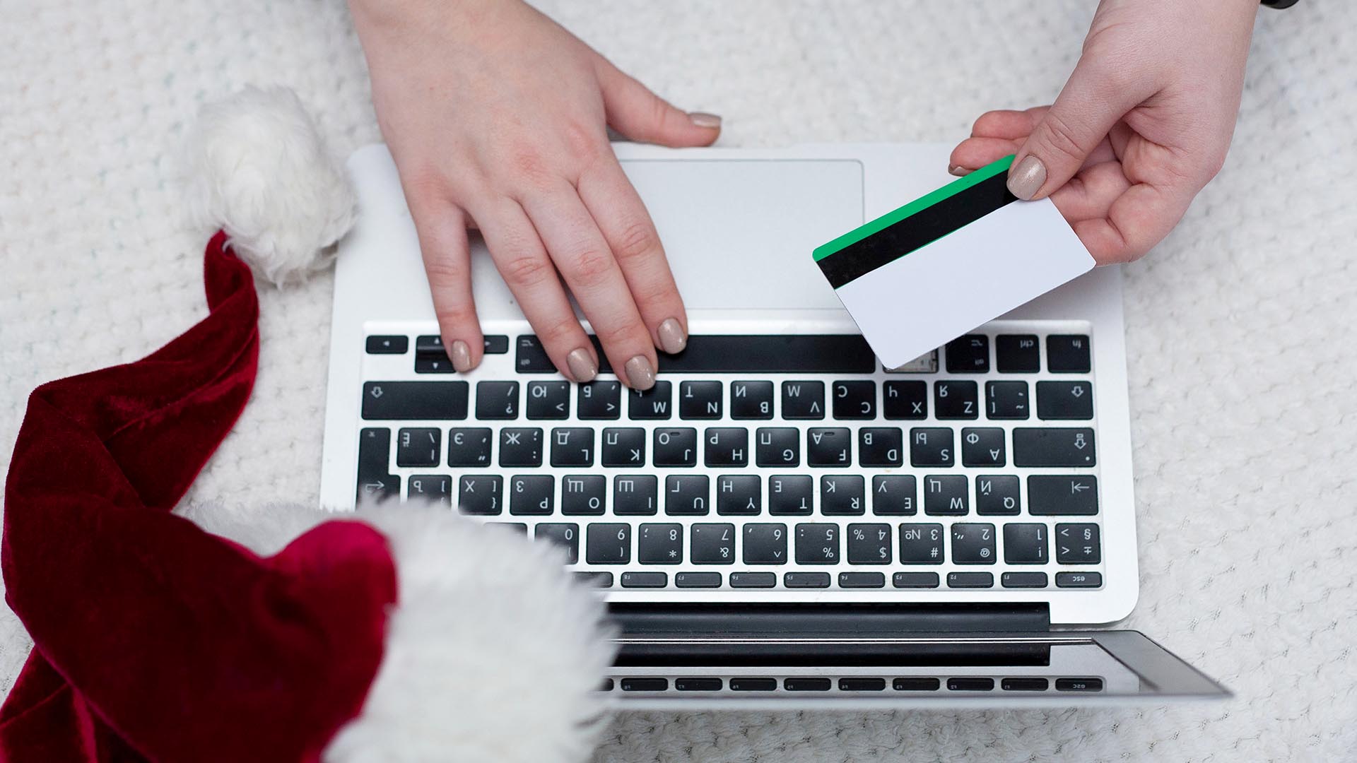 A woman orders gifts over the Internet. A woman's hand holds a credit card. Online ordering. Online shopping