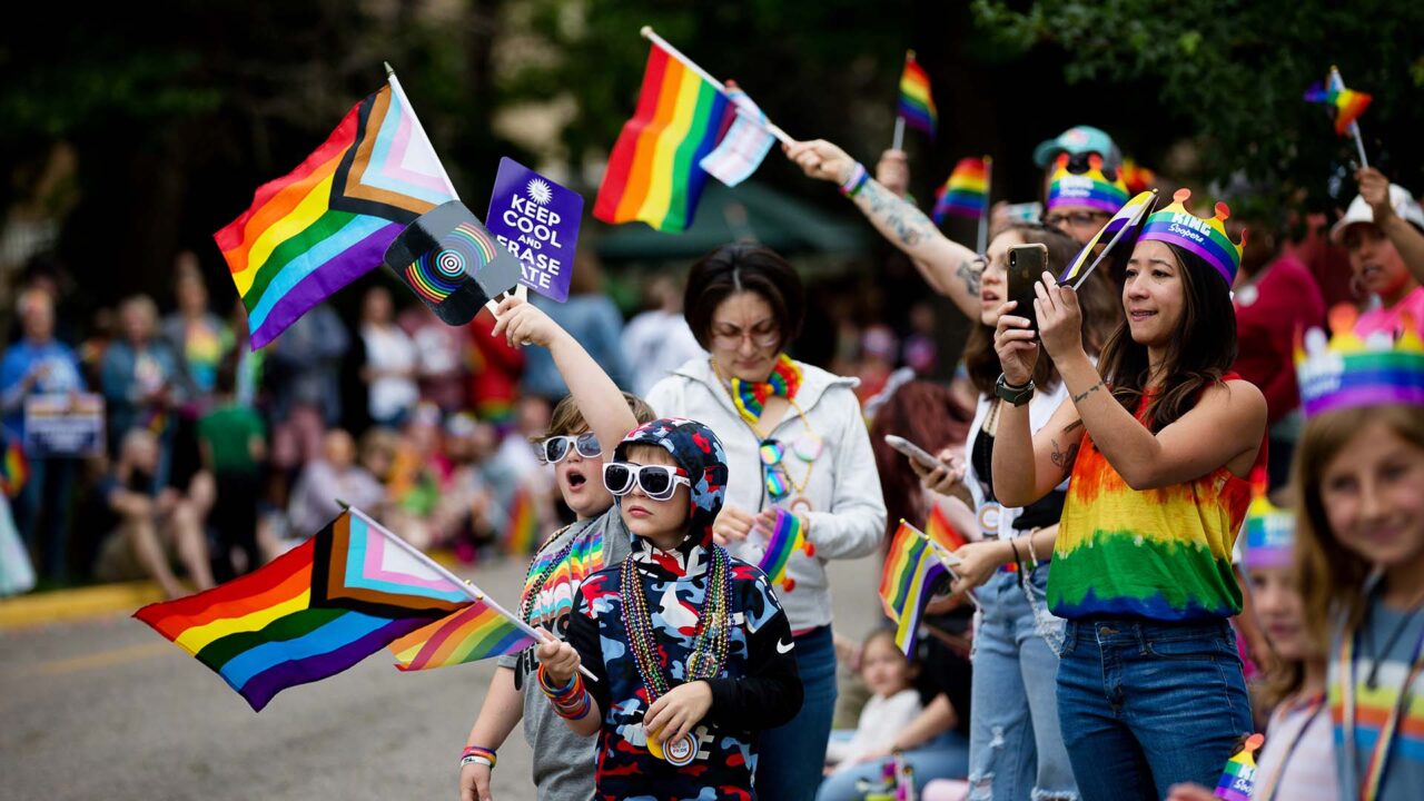 Spectators wave flags at the Denver Pride Parade