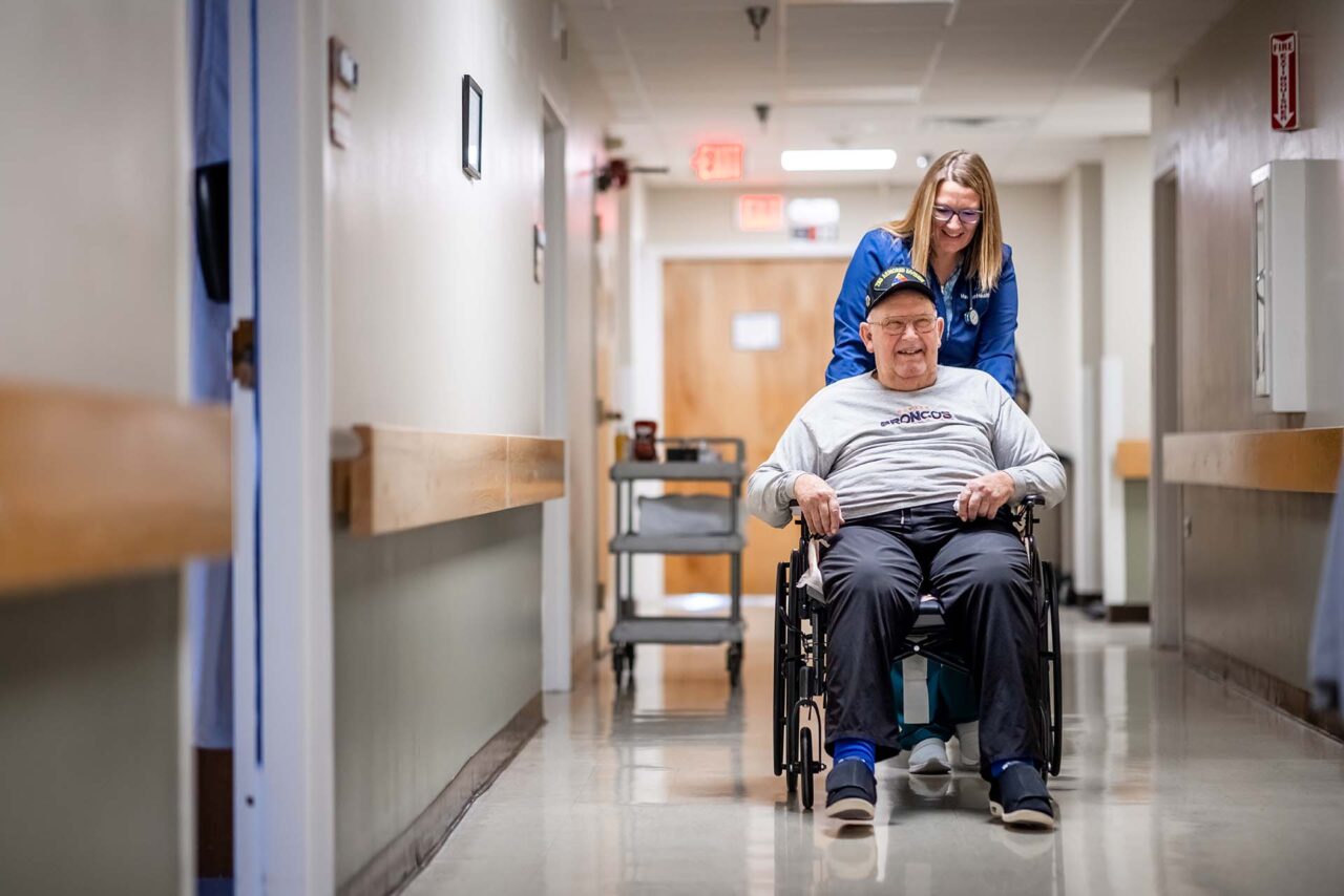 MSU Denver alumna Jessie Cochran assists resident Dennis “Cork” Bornhoft at Haxtun Health Hospital