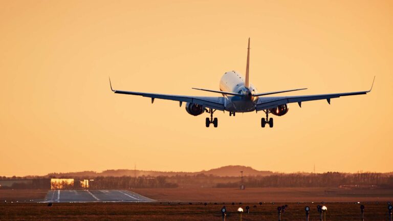 Airplane landing on runway. Traffic at airport at golden sunset.