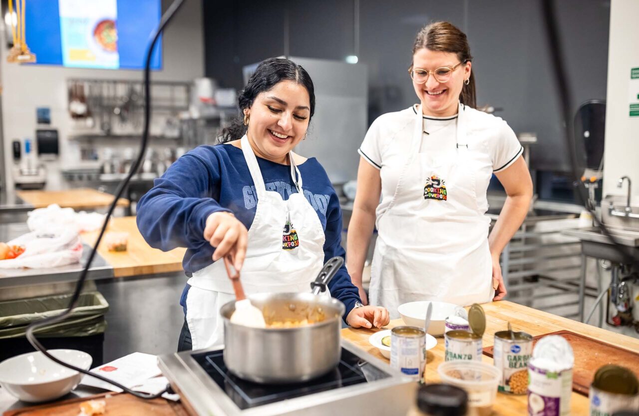 MSU Denver student Jeweliana Barron stirs the ingredients of chana masala during a Cooking with Purpose class as registered dietician Natalie Nowak looks on.