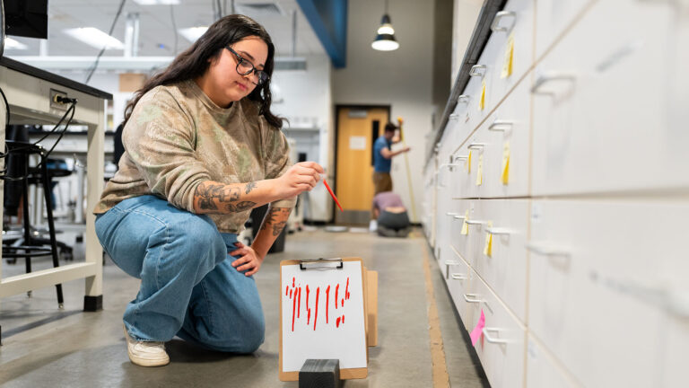 A student analyzes a red substance in a forensic lab during a crime scene investigation course.