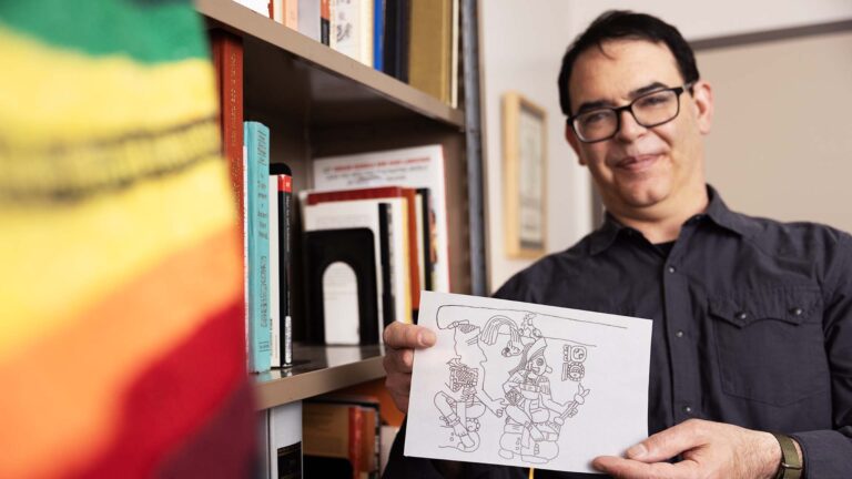 Associate professor Richard Sandoval holds an epigraphic line drawing he drew based off of his research