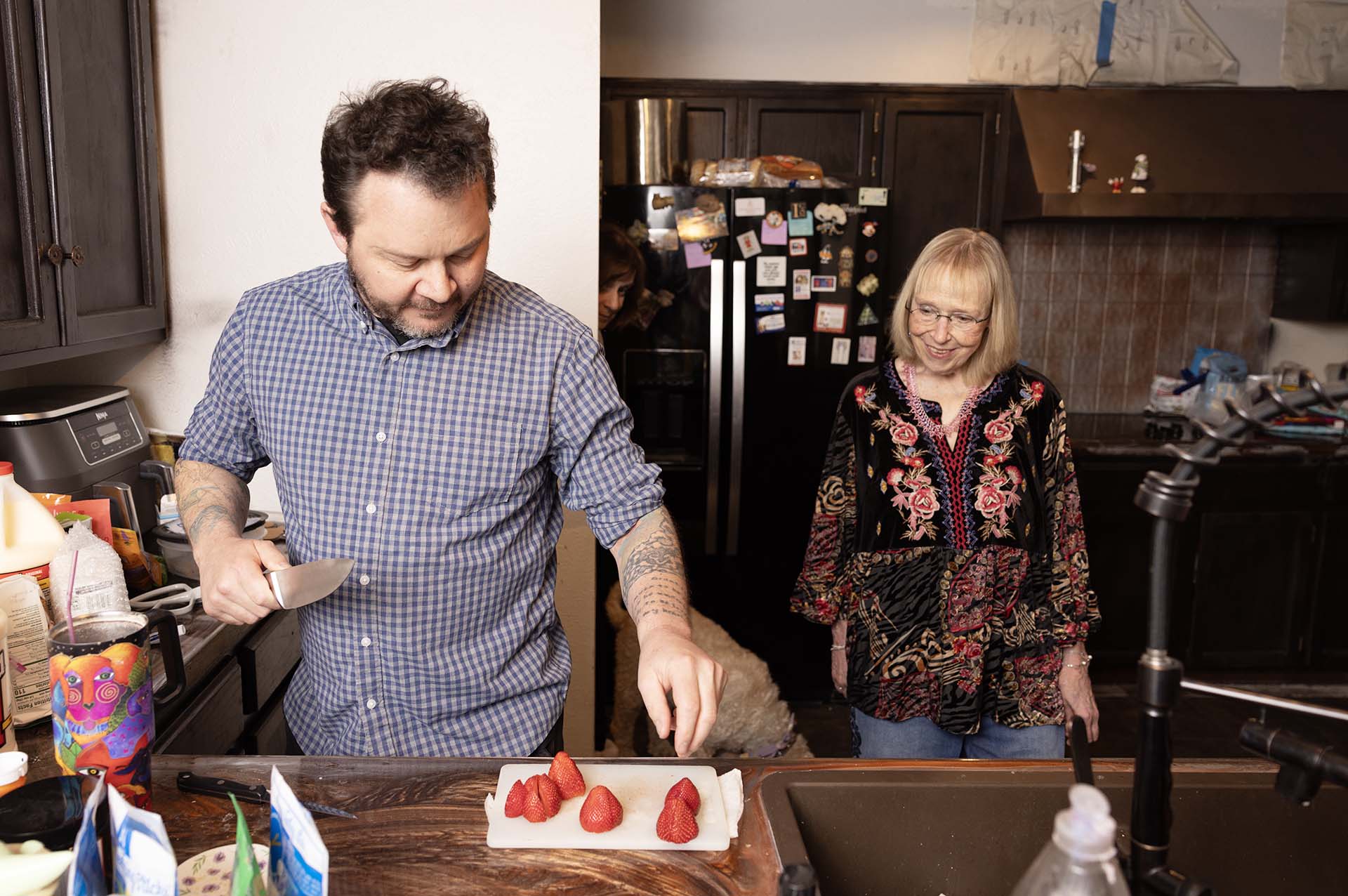 Christensen slices strawberries for the two of them to snack on in the kitchen