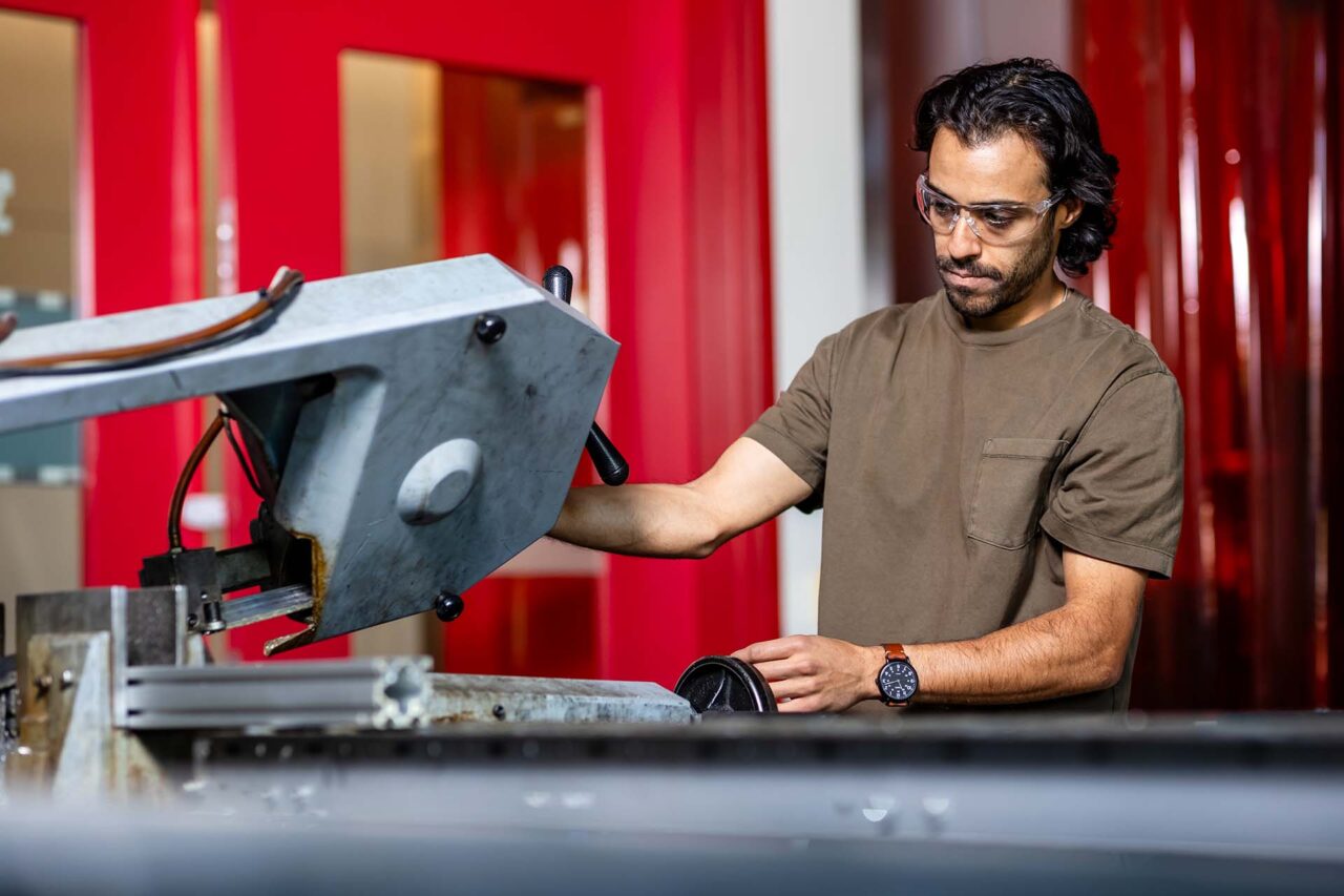 MSU Denver Advanced Manufacturing student Marco Antonacci cuts aluminum on a bandsaw.