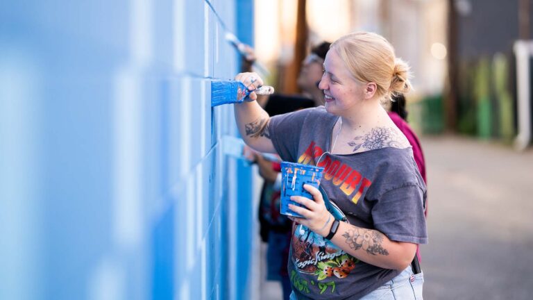 MSU Denver student Lillian Maley uses a brush to fill in a pattern on the Kalamath mural