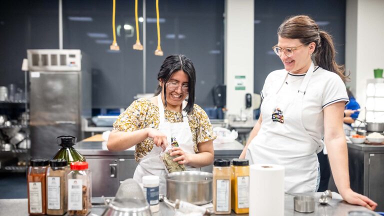 MSU Denver student Solange Cordova Santamaria adds seasoning to soup with registered dietician Natalie Nowak.