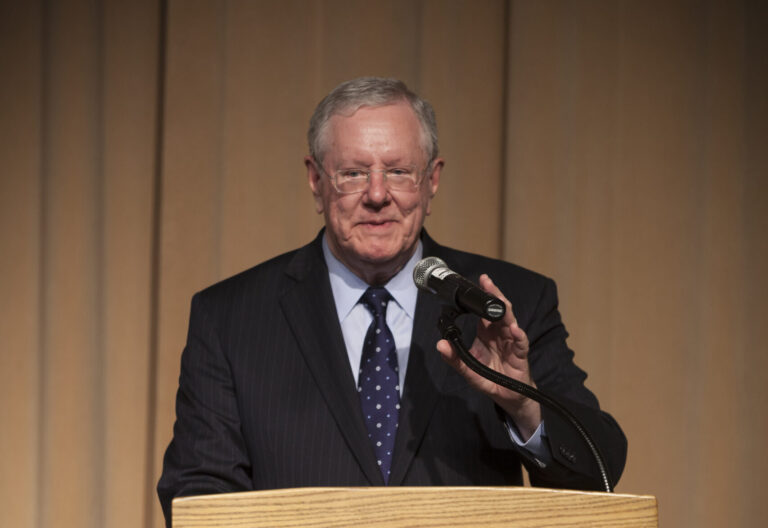 Steve Forbes stands at a podium in front of a microphone