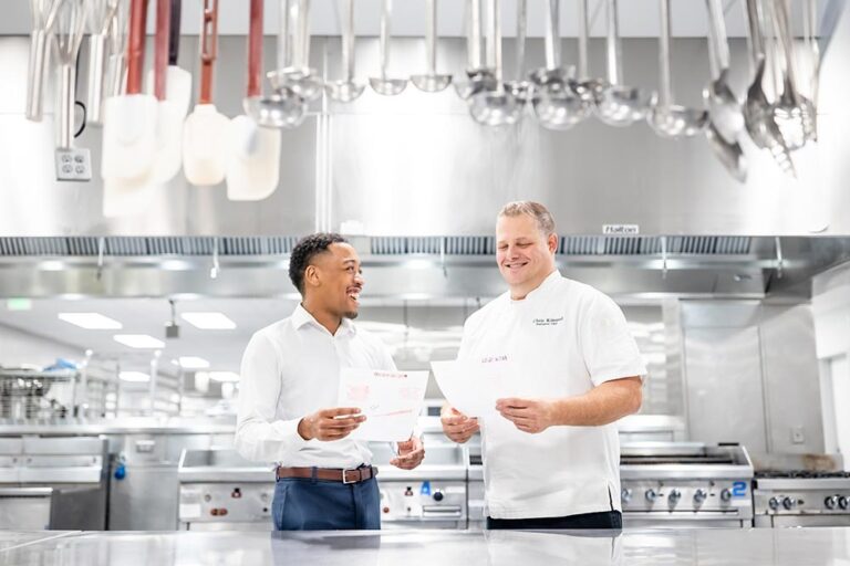 MSU Denver student stands in an industrial kitchen with a chef discussing catering plans