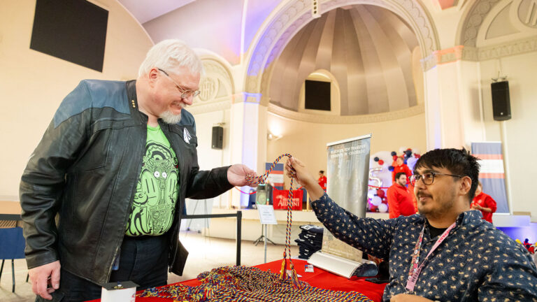 A person receives graduation cords from an MSU Denver staff member at a table inside St. Cajetan’s.