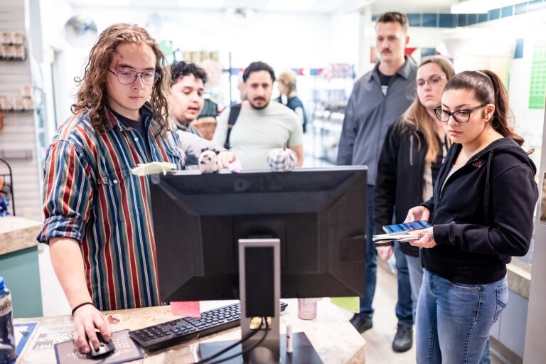 MSU Denver student and Rowdy's Corner employee Vann Whitson-DeHerrera demonstrates PantrySoft, the system used to track student points and item distribution, to MBA graduate students.