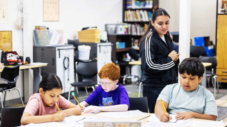 Meredith De La Torre checks out students Novan Trevino, Ned Barnhart and Julian Garcia's work during class.