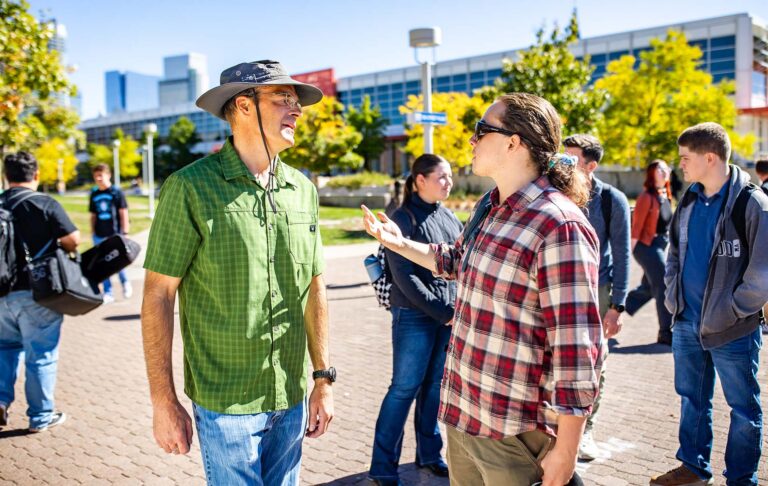 Robert Preuhs, Ph.D., has a discussion with student Vann Whitson-DeHerrera about current events outside the Emmanuel Art Gallery