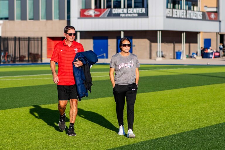 MSU Denver head women's soccer coach Katie Hooker and volunteer assistant coach Jeff Hooker walk onto the field to coach the team